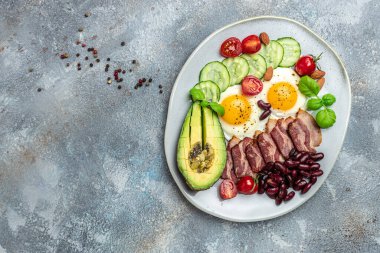 Sağlıklı besleyici paleo keto kahvaltı diyeti avokado, kızarmış yumurta, pastırma, fasulye ve kahve. Ketogenik diyet konsepti. Restoran menüsü, diyet, yemek kitabı tarifi üst görünümü.