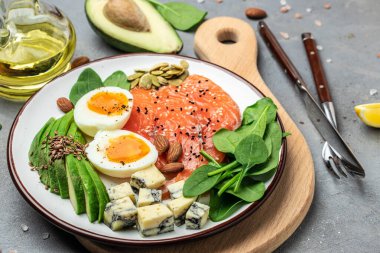 Diyet yiyecek, somon, avokado, peynir, yumurta, ıspanak ve fındık. afiş, menü, metin için tarif yeri, üst görünüm.