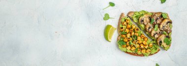 Healthy avocado toasts with chickpeas and mushrooms on a light background, vegetarian vegan food. Long banner format. top view. clipart