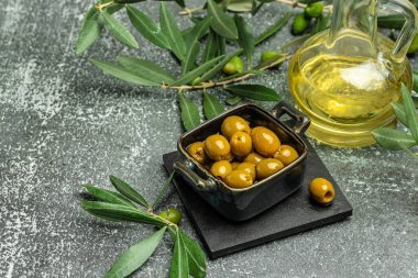 Zeytinli bir dal ve koyu arkaplanda bir şişe zeytin yağı. Üst Manzara. metin için yer,