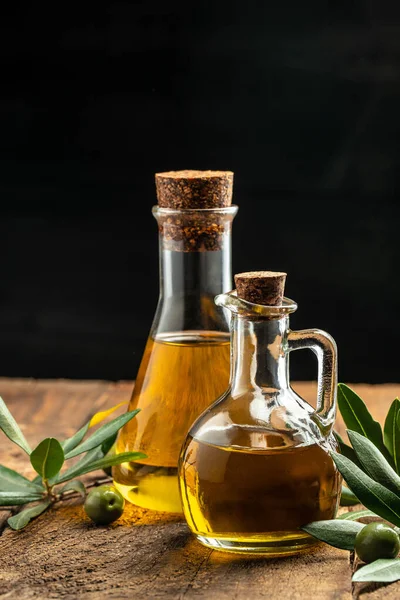 Olive oil in bottles with black and green olives and leaves. extra virgin olive oil jars on a wooden background. vertical image. top view. place for text.