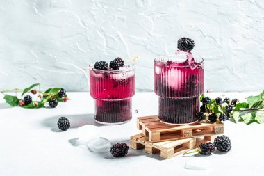 Blackberry mojito or lemonade with blackberry and ice Freeze motion splash drops on a light background. place for text.
