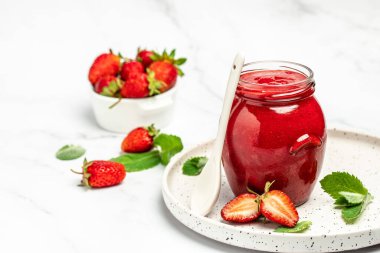 Kavanozda çilek reçeli ve beyaz masada taze böğürtlen. afiş, menü, metin için tarif yeri.