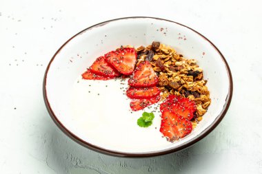 Yoğurtlu granola, taze çilek, chia tohumu ve bal beyaz arka planda. Lezzetli dengeli gıda konsepti. afiş, menü, metin için tarif yeri, üst görünüm.