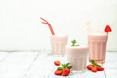 Meyveli smoothie. Çilekli smoothie ya da meyveli milkshake ve beyaz arka planda cam kavanozda yoğurt. Sağlıklı vejetaryen içeceği. Uzun afiş biçimi. en üstteki görünüm.
