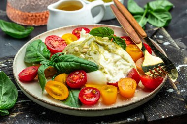 Salad burrata cheese tomatoes and green pesto. Delicious balanced food concept. superfood concept. Healthy, clean eating. Vegan or gluten free diet. top view.