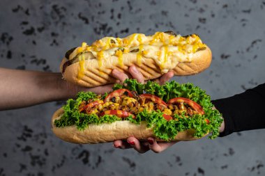 Sosisli sandviçleri çeşitli malzemelerle dolduran eller. Fast food sosisli sandviç, Amerikan sağlıksız kalori yemeği. afiş, menü, metin için tarif yeri,