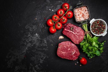 İki taze çiğ biftek ve arkaplanda pişmeye hazır baharatlar. Mutfak, yemek pişirme, konsept. afiş, menü, metin için tarif yeri, üst görünüm.