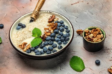 Kahvaltıda yulaf lapası, fındıklı yulaf ezmesi, fındıklı taze yaban mersinli bal. Vejetaryen vejetaryen yemeği yiyen süper sağlıklı yiyecekler. en üstteki görünüm.