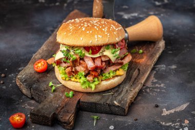 Sığır etli, domatesli, peynirli ve marullu ızgara burger. Fast food ve abur cubur kavramı.