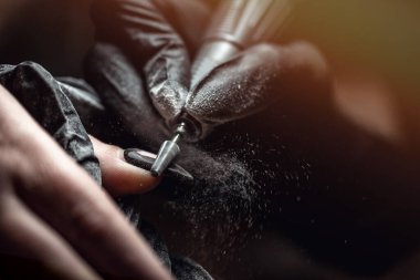 Usta, kuaförde manikür yaparken ojeyi çıkarmak için elektrikli makine kullanıyor. Donanım manikürü