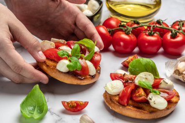 Kadın elleri mutfakta Caprese Bruschetta 'yı hazırlıyor. Lezzetli kahvaltı ya da atıştırmalık, temiz yemek, diyet, vejetaryen yemek konsepti. en üstteki görünüm.