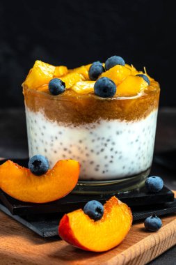 yogurt dessert with peaches blueberry chia on a dark background. Natural detox, fruit dessert, healthy dieting concept.