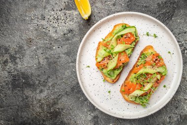İki tost, tuzlanmış somon, avokado ve taze yeşillikler. Süper yiyecek konsepti. Sağlıklı, temiz yemek. Vejetaryen ya da glütensiz diyet. en üstteki görünüm.