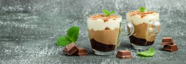 Naneli bir bardakta üç kremalı çikolata. Lezzetli bir tatlı. Uzun pankart biçimi.