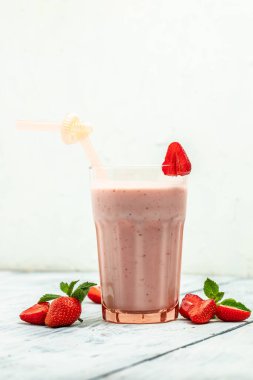 Çilekli smoothie ya da meyveli milkshake ve beyaz beton arka planda cam kavanozda yoğurt. Sağlıklı vejetaryen içeceği. metin için yer,