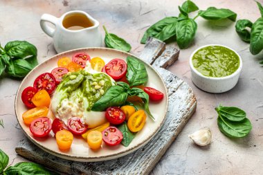 Salad burrata cheese tomatoes and green pesto. Delicious balanced food concept. superfood concept. Healthy, clean eating. Vegan or gluten free diet. top view.