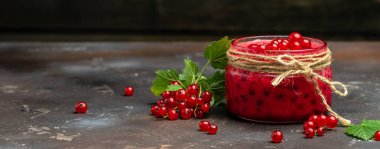 Kavanozda frenk üzümü reçeli. Karanlık bir arka planda taze meyve konservesi. Uzun pankart biçimi.