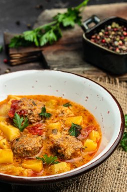 Etli, patatesli, soğanlı güveç, domates soslu kabak, sarımsak ve otlar beyaz kasede, dikey görüntü. Üst Manzara. metin için yer.