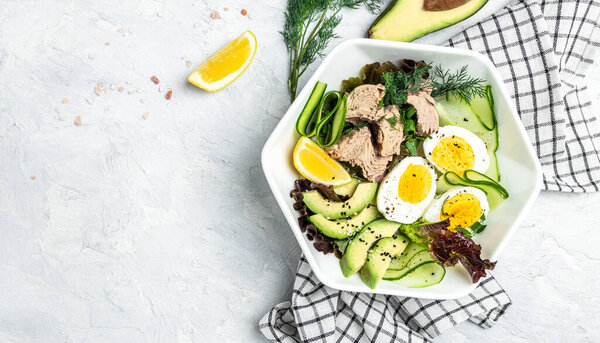 Ketogenic low carbs diet, Plate with keto foods: two eggs, avocado, tuna, cucumber and fresh salad. Healthy fats, clean eating for weight loss. top view.