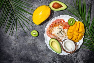 Avokado, karides, pilav, mango, kivi ve hindistan cevizli dürtme kabı. Sağlıklı ve dengeli bir yemek. afiş, metin için menü tarifi yeri, üst görünüm