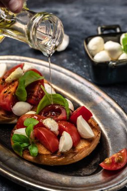 Mozzarella, kiraz domatesli ve taze fesleğenli Caprese tostları. Geleneksel İtalyan aperatifi veya aperatifi, antipasto. dikey görüntü. Üst Manzara. metin için yer,