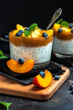 homemade dessert with fruits, parfait yogurt with peaches blueberry and chia. place for text.