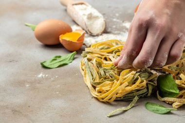 Çiğ sarı ev yapımı İtalyan makarnası, fetuçin ya da tagliatelle tutan kadın elleri. Yemek tarifi geçmişi. Kapat..