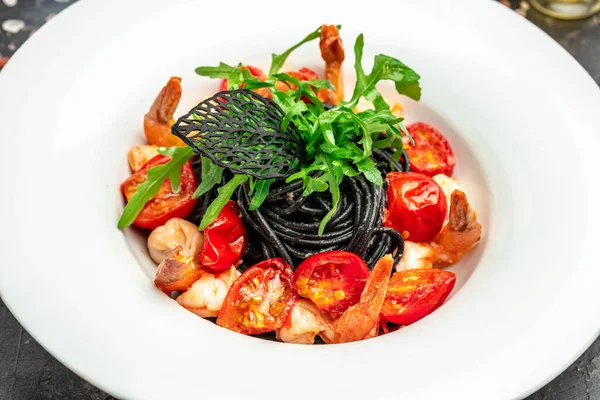black pasta with shrimp and cherry tomatoes. Delicious balanced food conceptDelicious balanced food concept.