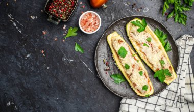 Koyu bir arka planda kıyma ve peynirle doldurulmuş kabak. Restoran menüsü, diyet, yemek kitabı tarifi üst görünümü.