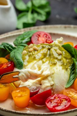 Salad burrata cheese tomatoes and green pesto. Delicious balanced food concept. superfood concept. Healthy, clean eating. Vegan or gluten free diet. top view.