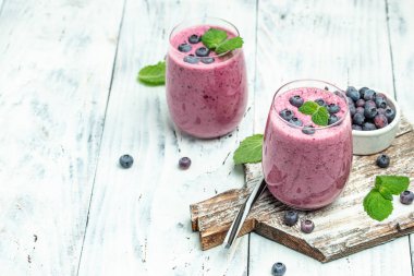 Hafif arka planda cam kaplı yabanmersinli smoothie. Lezzetli dengeli gıda konsepti. en üstteki görünüm,