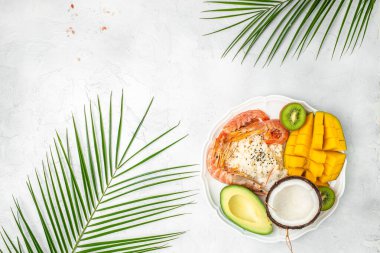 Avokado, karides, pilav, mango, kivi ve hindistan cevizi, deniz sahilinde tropikal yiyecekler, organik ve sağlıklı yiyecekler, yazı için yer, üst görüş.,