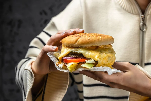 the girl is biting a burger with melted cheese, Fast food take away copy space,