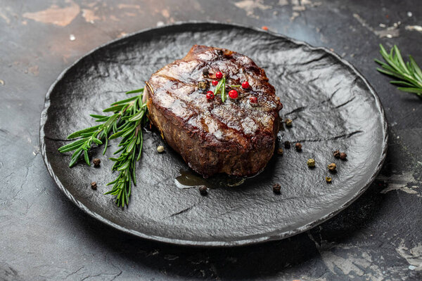 Grilled meat steak Filet Mignon with seasonings. Juicy meat steak on a dark background. Food recipe background. Close up.