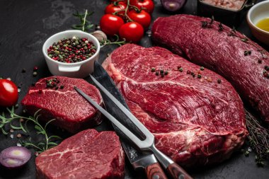 Biftek arka planda biftek, otlar ve baharatlarla birlikte koyu bir arka planda. Restoran menüsü, diyet, yemek kitabı tarifi üst görünümü,