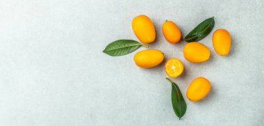 Raw orange kumquats on a light background, organic food market. Long banner format. top view.