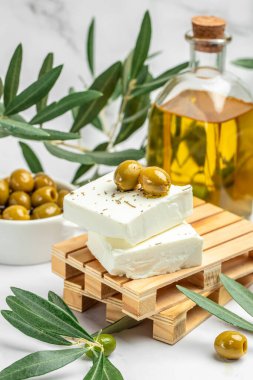 Feta Greek cheese with olives and olive oil on light background. vertical image. top view. place for text.