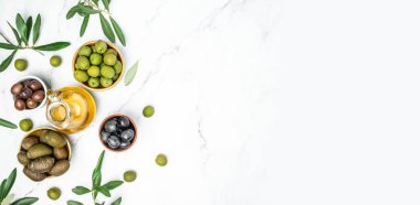 Ahşap kaselerde zeytin, arka planda cam şişelerde yağ. Sağlıklı ve detoks gıda konsepti.