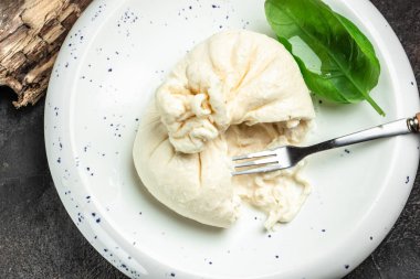 Basil yapraklı burrata peyniri beyaz tabakta koyu arkaplanda. afiş, menü, metin için tarif yeri, üst görünüm.