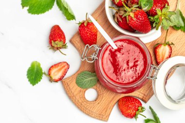 Kavanozda çilek reçeli ve beyaz masada taze böğürtlen. afiş, menü, metin için tarif yeri.