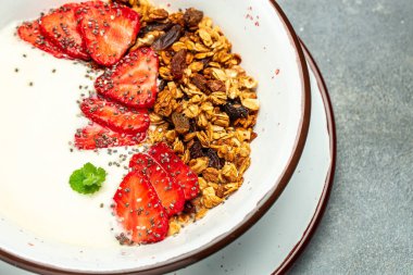 Yoğurtlu granola, taze çilek, chia tohumu ve bal beyaz arka planda. Lezzetli dengeli gıda konsepti. afiş, menü, metin için tarif yeri, üst görünüm.