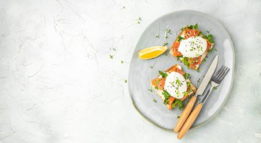 healthy breakfast with poached eggs, salmon and guacamole on toast. Long banner format. top view.
