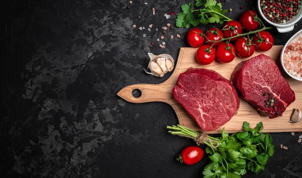 raw cuts of raw beef meat steaks on dark background, banner, menu, recipe place for text, top view.
