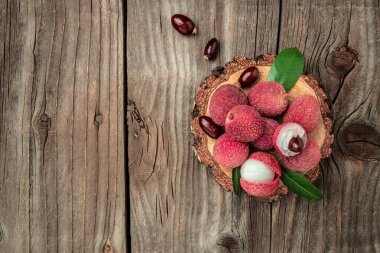 fresh ripe lychee fruit and peeled lychee with green leaves on a wooden background. banner, menu, recipe place for text, top view.