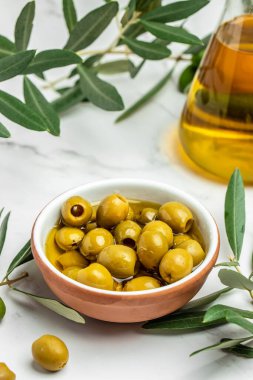 Branch with olives and a bottle of olive oil on light background. vertical image. top view. place for text.