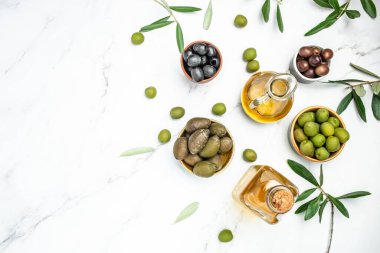 İki cam kapta zeytinyağı ve hafif arka planda zeytin meyveleri.