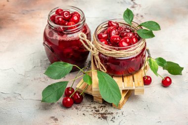 Kavanozda kiraz reçeli ve masada taze böğürtlen. Arka planda bahçeden gelen organik gıdalar korunmuş. afiş, menü, metin için tarif yeri.