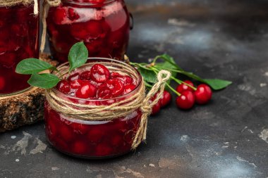 Kavanozda kiraz reçeli ve masada taze böğürtlen. Bahçedeki organik yiyecekleri karanlık bir arka planda saklamış. afiş, menü, metin için tarif yeri.