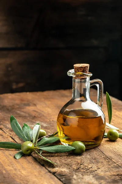 Olive oil in bottles with black and green olives and leaves. extra virgin olive oil jars on a wooden background. vertical image. top view. place for text.